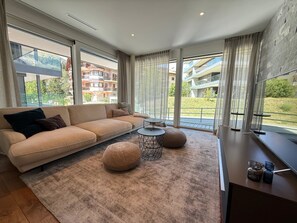 Ein modernes Wohnzimmer mit einer Couch, runden Hocker, einem Couchtisch und einem Fernseher.