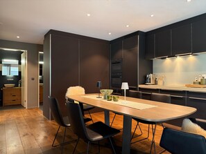 Eine moderne Küche mit dunklen Schränken, einem Holztisch und schwarzen Stühlen.