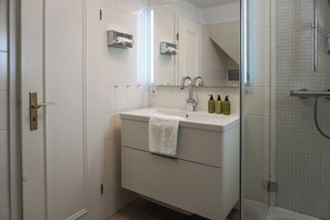 A modern bathroom with a white sink, mirror, and shower. - Comfortable apartment in Keitum with a beach chair on Kampen Beach (Sylt)