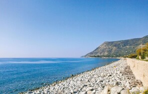 A coastal landscape with a rocky shoreline, clear blue sea, and a mountain in the background. - Cozy home in Nicotera Marina with swimming pool (Nicotera Marina)
