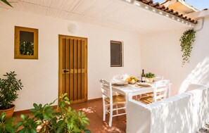 A patio with a white table set for dining, surrounded by white chairs, a wooden door, and potted plants. - Cozy home in Nicotera Marina with swimming pool (Nicotera Marina)