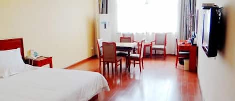 Habitación de hotel con cama, escritorio, silla, televisor y ventana con cortinas.