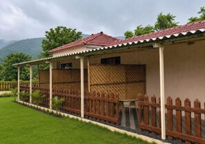 A two-story building with a red-tiled roof, wooden fence, and a covered patio area.