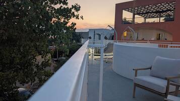 A balcony with a white railing, a swing, and a seating area with a cushion.