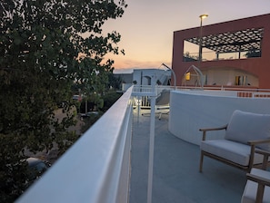 A balcony with a white railing, a swing, and a seating area with a cushion.
