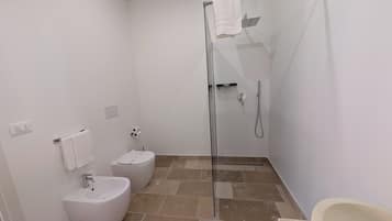 Ein modernes Badezimmer mit einer Duschkabine, einer Toilette und einem Bidet.