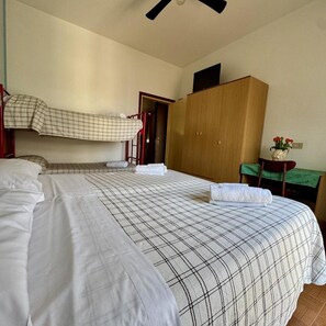 A room with a bunk bed, a wooden wardrobe, a desk with a vase of flowers, and a green tablecloth. - Arborea (Jesolo)