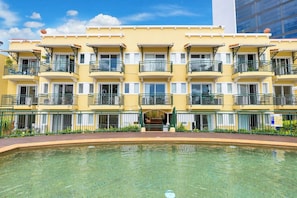 Un hôtel à plusieurs étages doté de balcons, d’une piscine et offrant une vue sur un ciel dégagé.