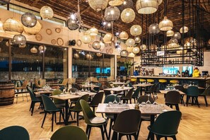 A restaurant interior with multiple dining tables, chairs, hanging spherical light fixtures, and a bar area. - Tulum Beach Resort & Spa Dakhla (Dakhla)
