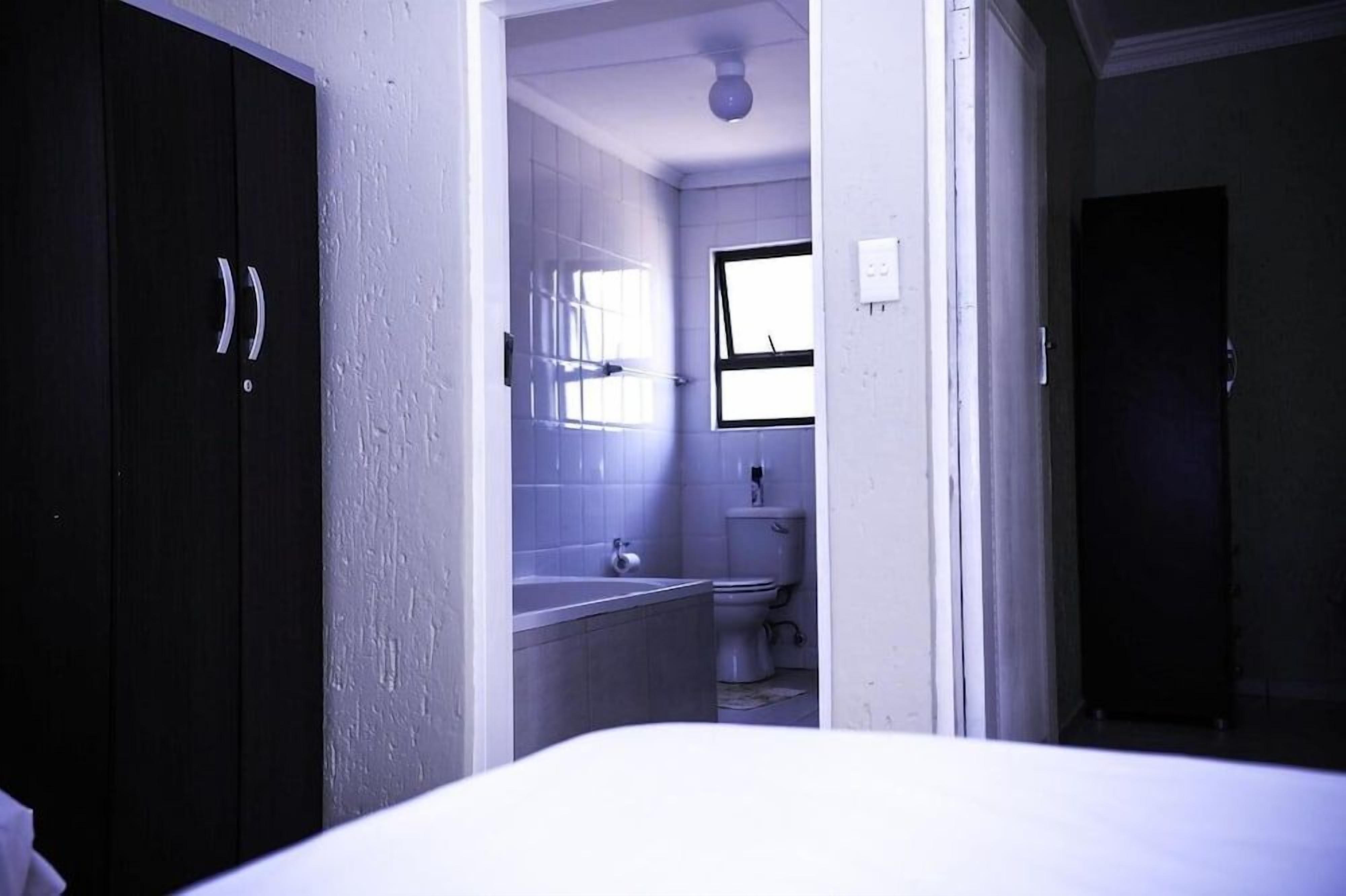 A bathroom with a toilet, sink, and window.
