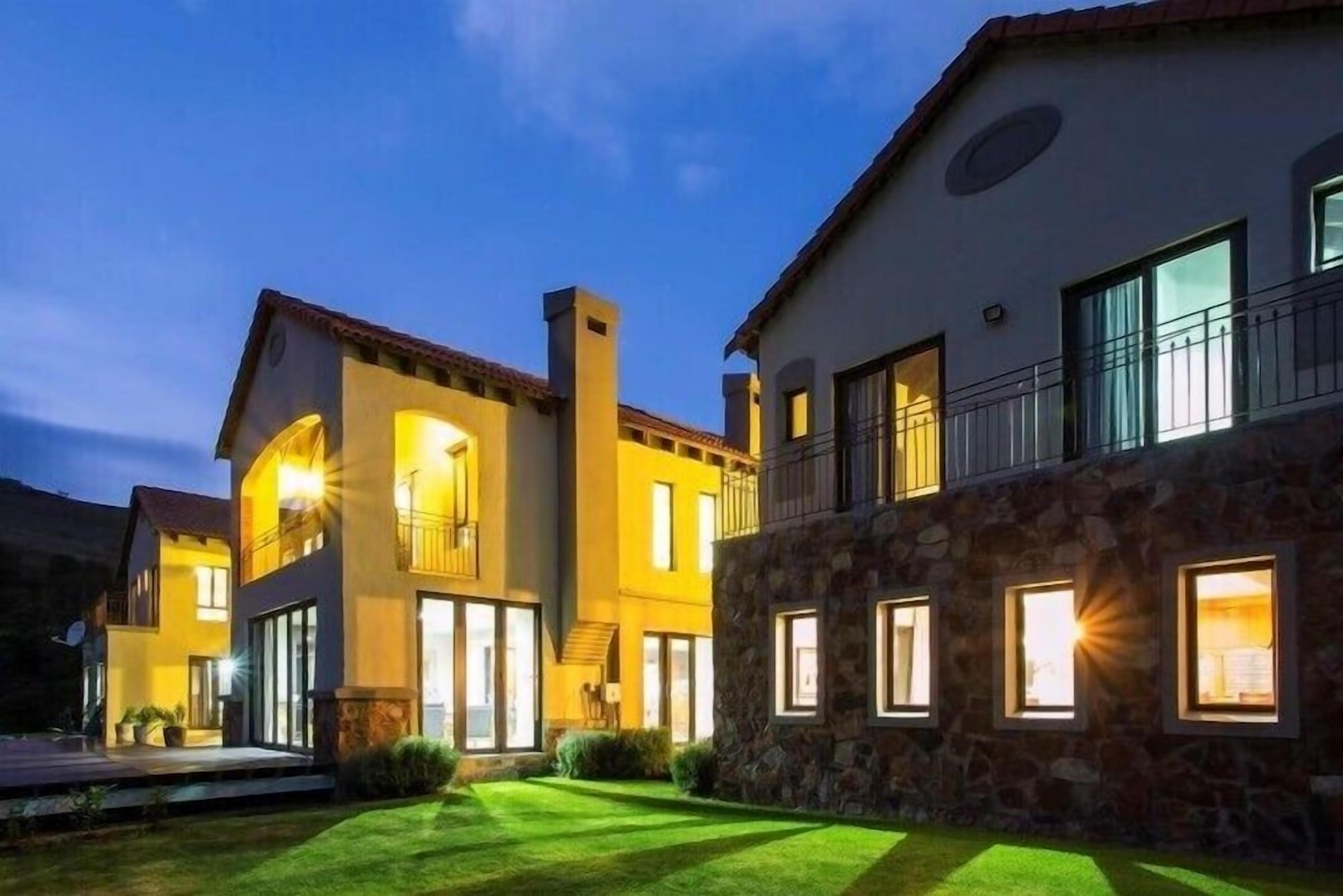 A multi-story residential building with a well-lit exterior, a stone facade, and a visible balcony.
