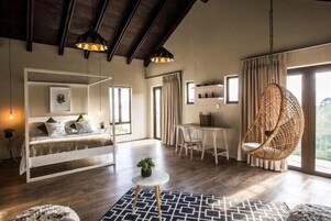 Una habitación con cama, una silla colgante, una mesa de comedor y una mesita con una planta.
