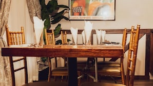 A dining table set with chairs, a framed picture on the wall, and a potted plant. - Ngwenya City Hotel (Klerksdorp)