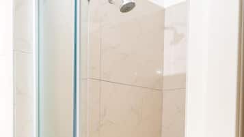 A glass-enclosed shower with a handheld showerhead.