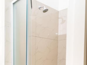 Una cabina doccia in vetro con soffione manuale.