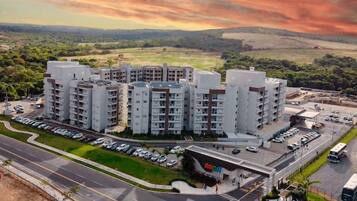 Edifício residencial com vários andares, um estacionamento e uma estrada ao primeiro plano.