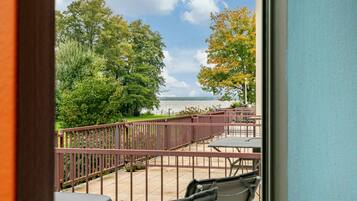 Ein Balkon mit Blick auf ein Gewässer, umgeben von Bäumen und einem Metallgeländer.
