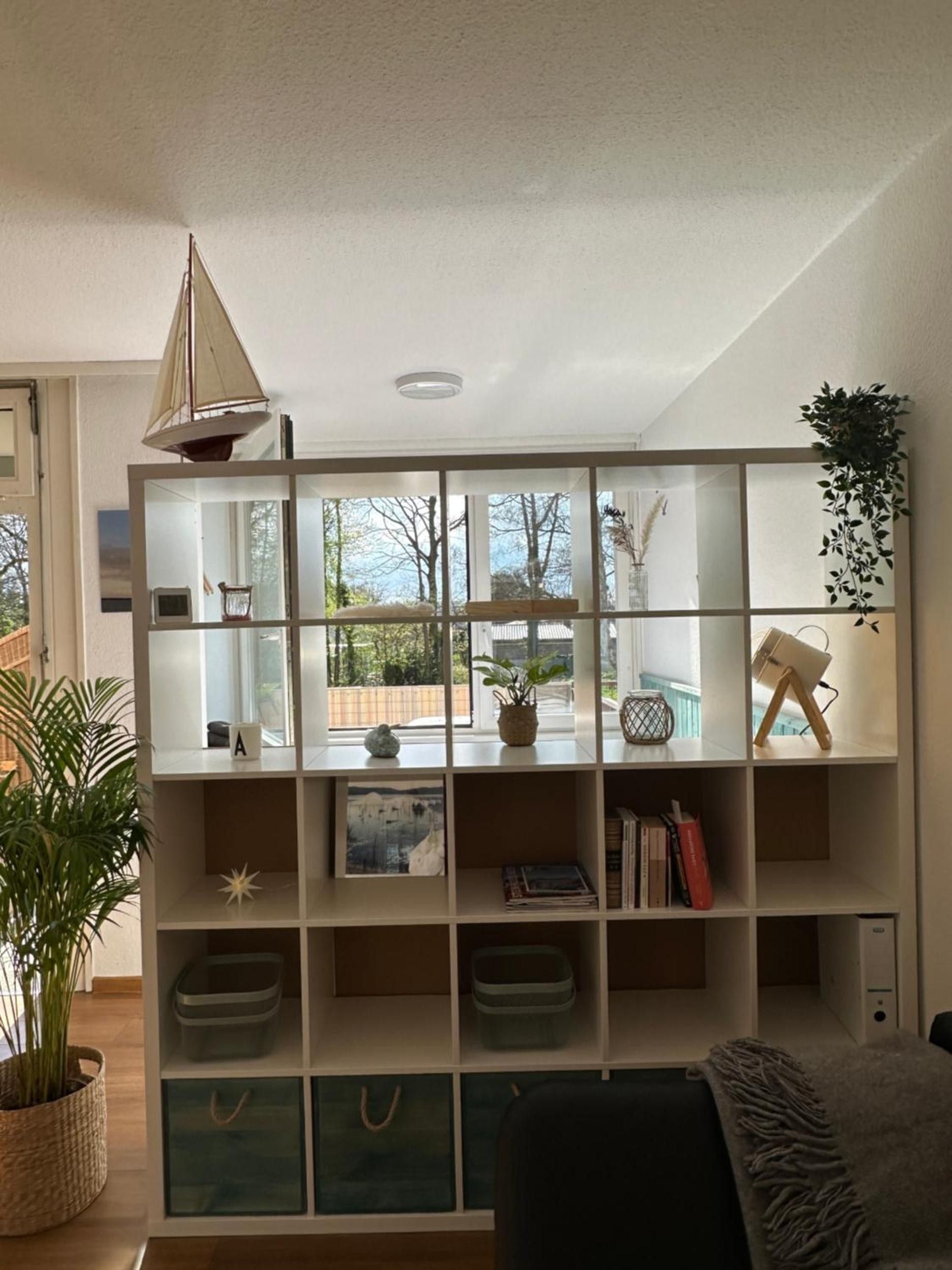 Una sala de estar moderna con una amplia estantería, una lámpara colgante y vistas al exterior.