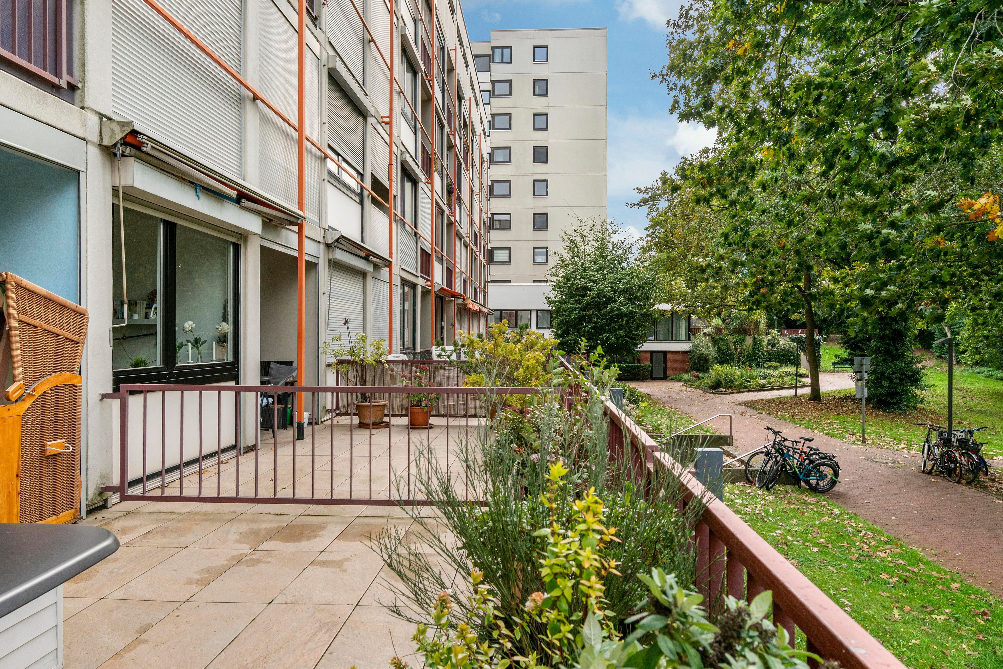 Ein Wohngebäude mit Balkon, Sitzgelegenheit im Freien und einem abgestellten Fahrrad.