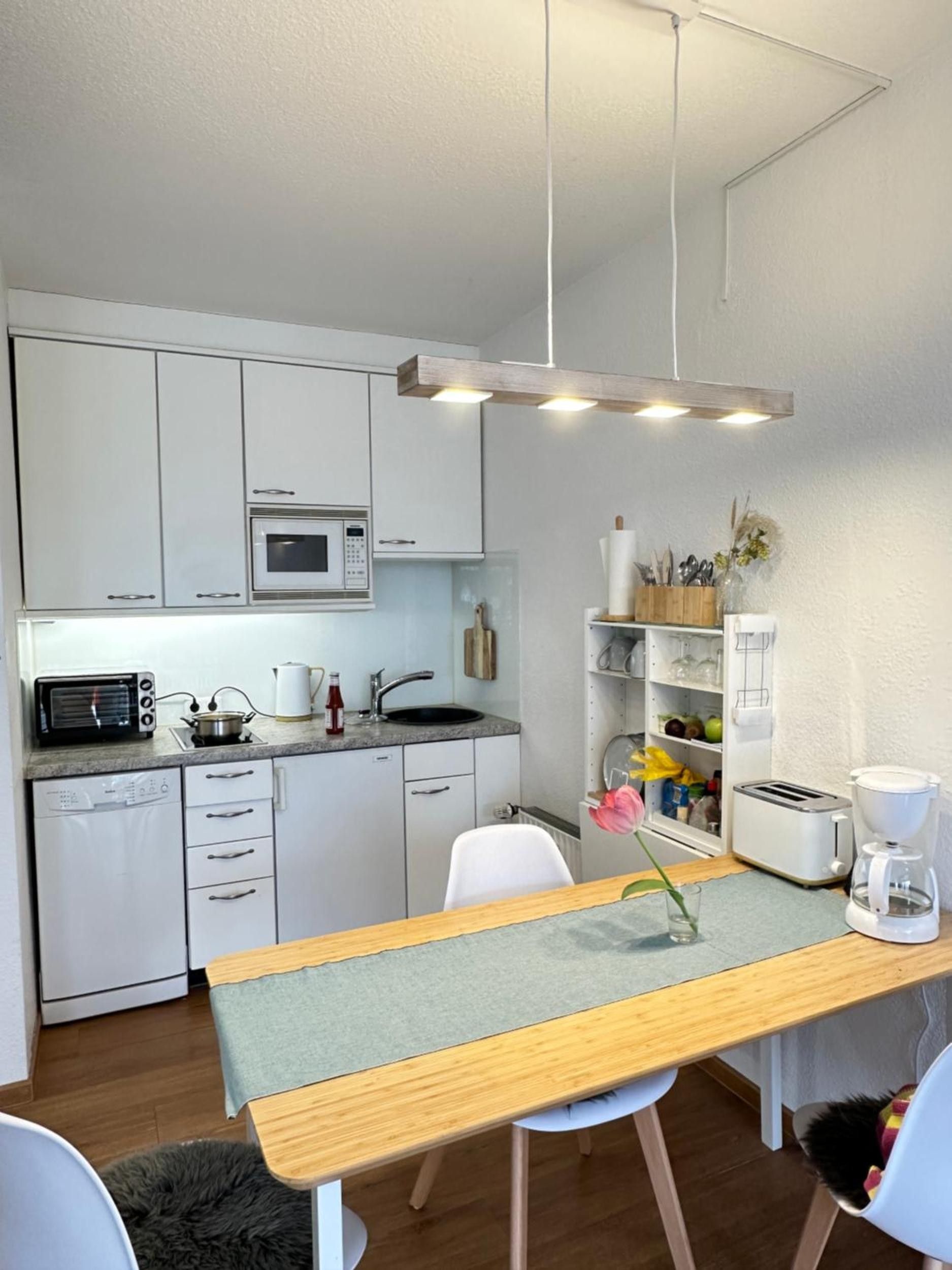 Eine kleine Küche mit weißen Schränken, einer Mikrowelle, einem Toaster und einer Kaffeemaschine.