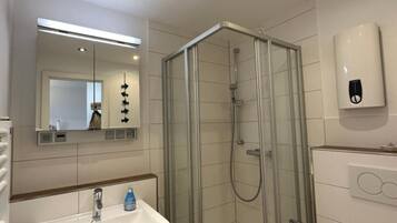 Ein modernes Badezimmer mit einer Duschkabine, einem Waschbecken mit Spiegel darüber und einer Toilette.
