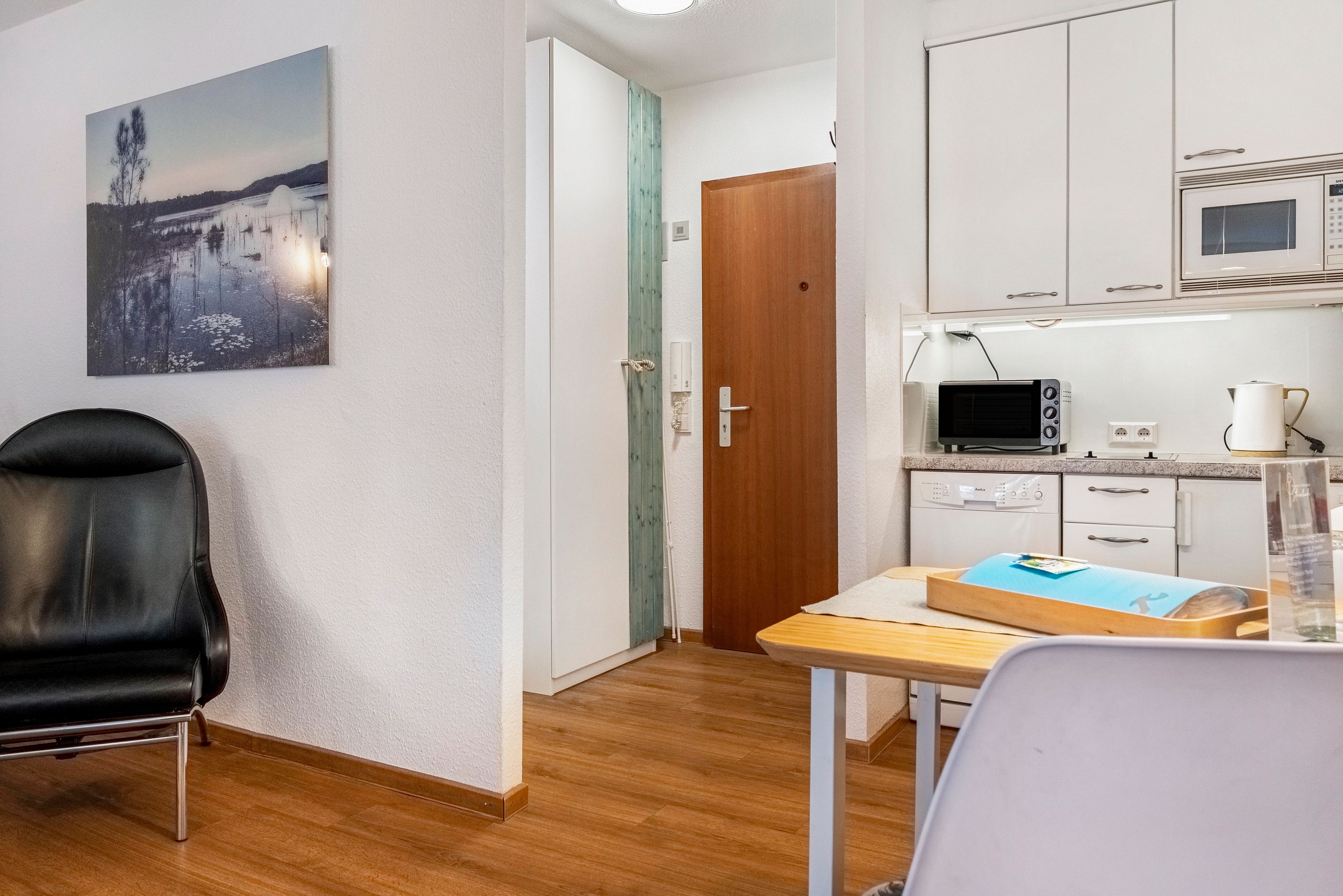 A modern kitchen with white cabinets, a microwave, and a coffee maker.