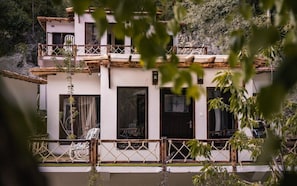 A two-story building with a balcony, wooden railings, and a view of a mountainous landscape.