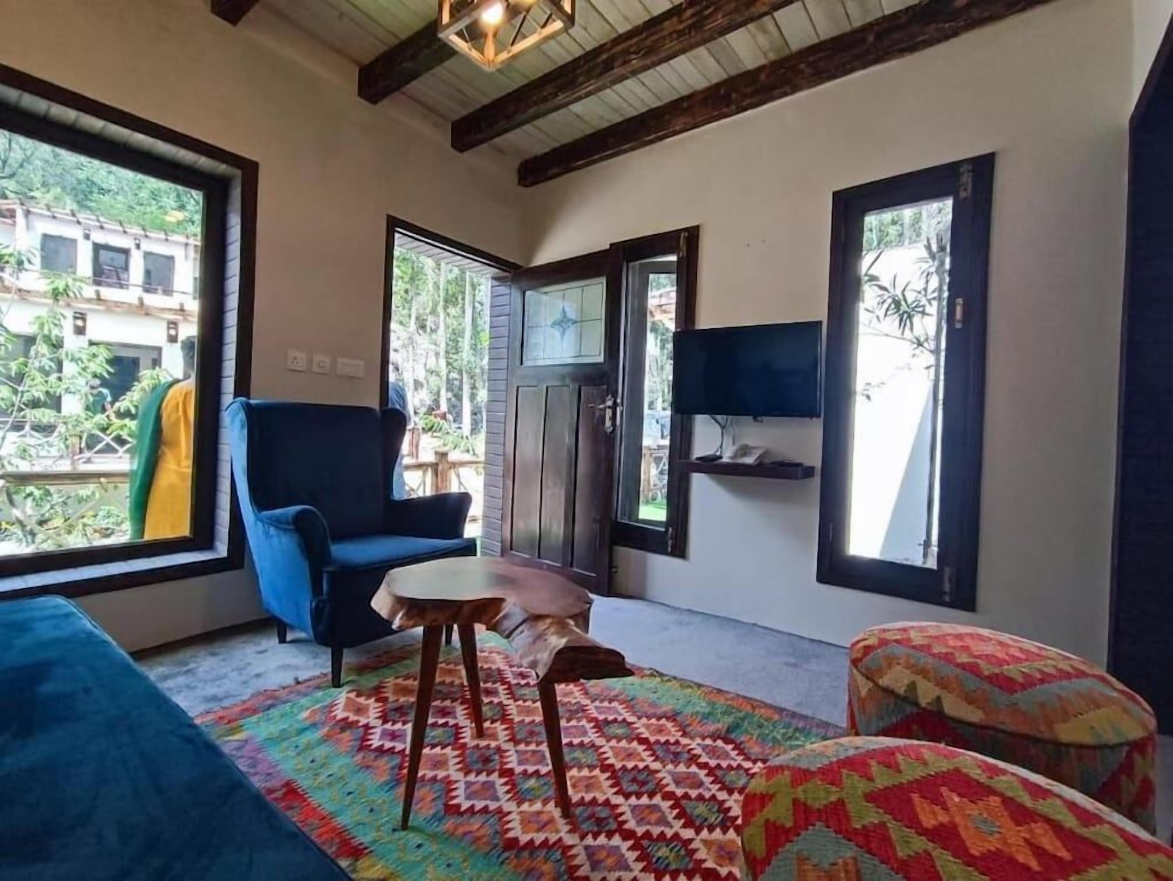 A room with a blue sofa, a patterned rug, a wooden table, and a television mounted on the wall.