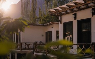 Un edificio con balcón, barandilla de madera y montañas al fondo.