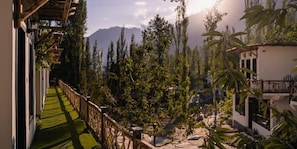 A balcony with a view of a garden and mountains.