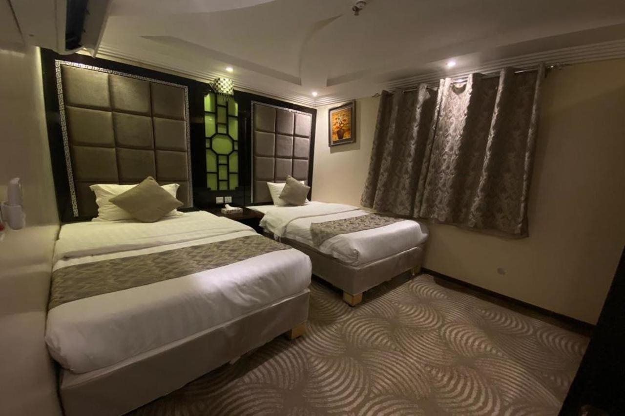 Une chambre d’hôtel avec deux lits, une moquette à motifs et une grande fenêtre avec des rideaux.