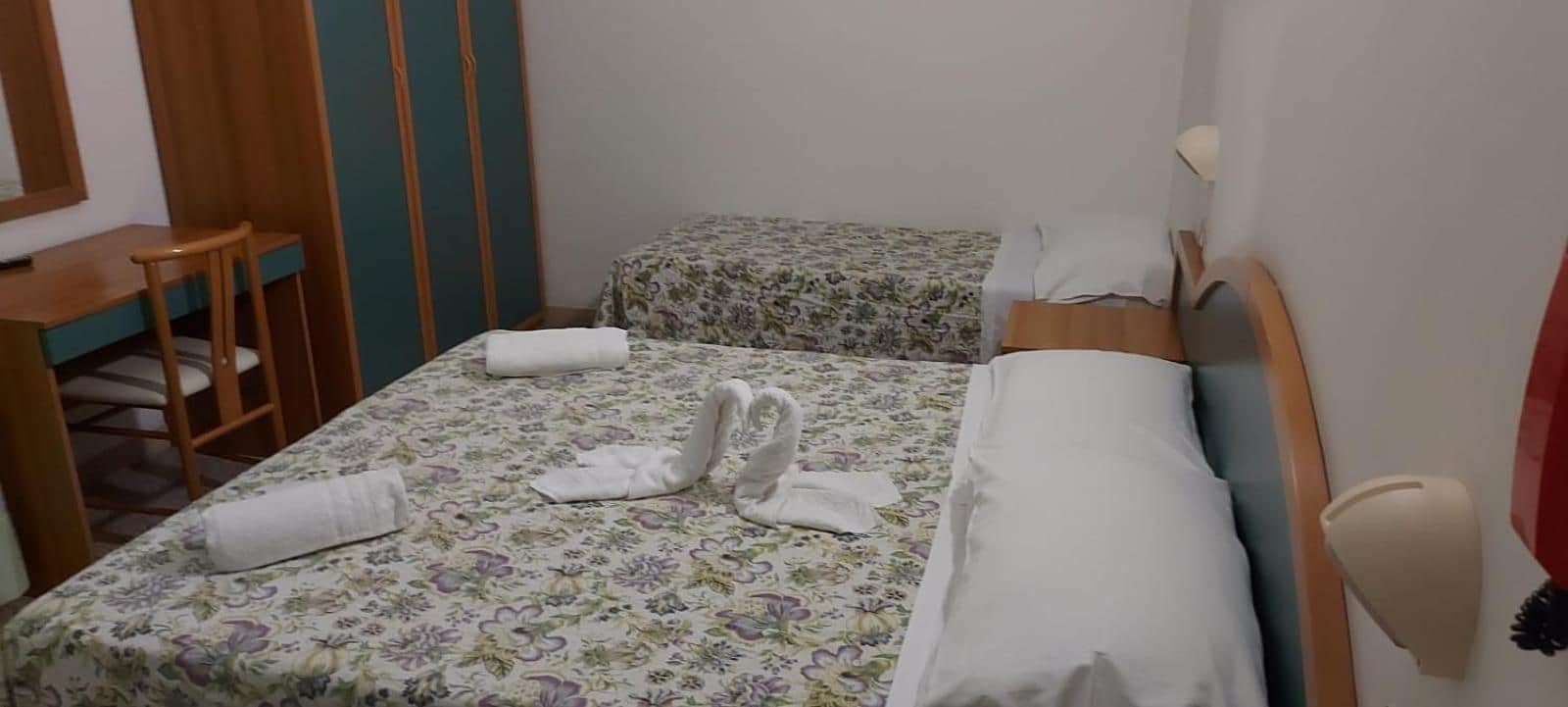 A room with two beds, a desk, and a chair.