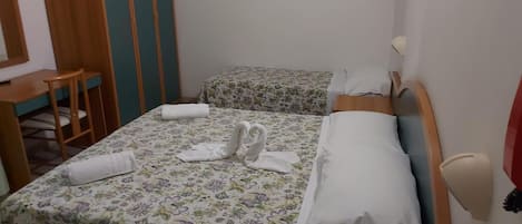 A room with two beds, a desk, and a chair.