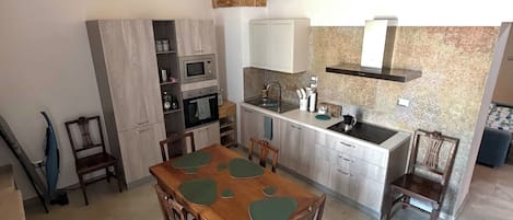 A spacious kitchen with a stone ceiling, a dining table with chairs, and a built-in oven.