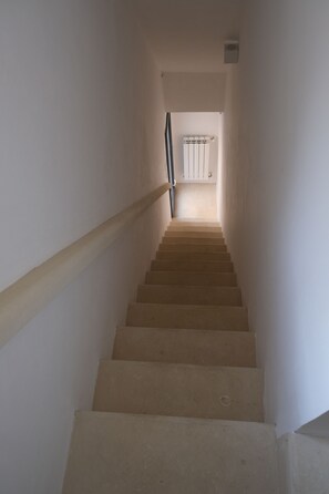 A staircase leading to a landing with a radiator and a window. - Stella del Salento – Historic residence with a private terrace (Tricase)