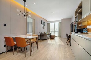A modern kitchen with built-in appliances, a dining area with a table and chairs, and a large window providing natural light. - Home2 Suites by Hilton Shenzhen Nanshan Science & Technology Park (Shenzhen)