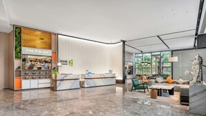 Una hall d'albergo con reception, area salotto e caffetteria.