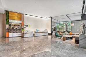 A hotel lobby with a reception desk, seating area, and a coffee shop. - Home2 Suites by Hilton Shenzhen Nanshan Science & Technology Park (Shenzhen)