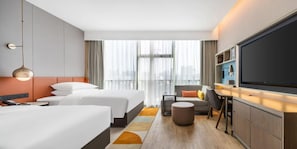 A hotel room with two beds, a TV, a desk, and a view of the city. - Home2 Suites by Hilton Shenzhen Nanshan Science & Technology Park (Shenzhen)