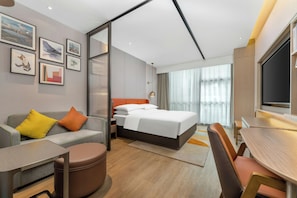 A modern hotel room with a bed, a sofa, a desk, and a TV. - Home2 Suites by Hilton Shenzhen Nanshan Science & Technology Park (Shenzhen)