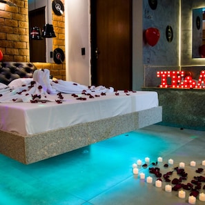 A modern bedroom with a bed, rose petals, candles, and a neon sign. - Miragem Motel (Rio Verde)