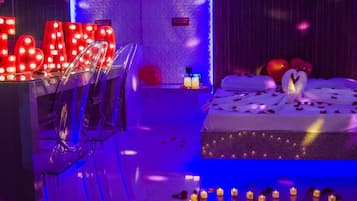 Um quarto com uma cama, uma escrivaninha com letras iluminadas e velas no chão.