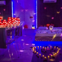 Um quarto com uma cama, uma escrivaninha com letras iluminadas e velas no chão.