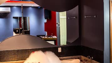 Um quarto de spa com banheira, espelho e decoração de parede em vermelho e preto.