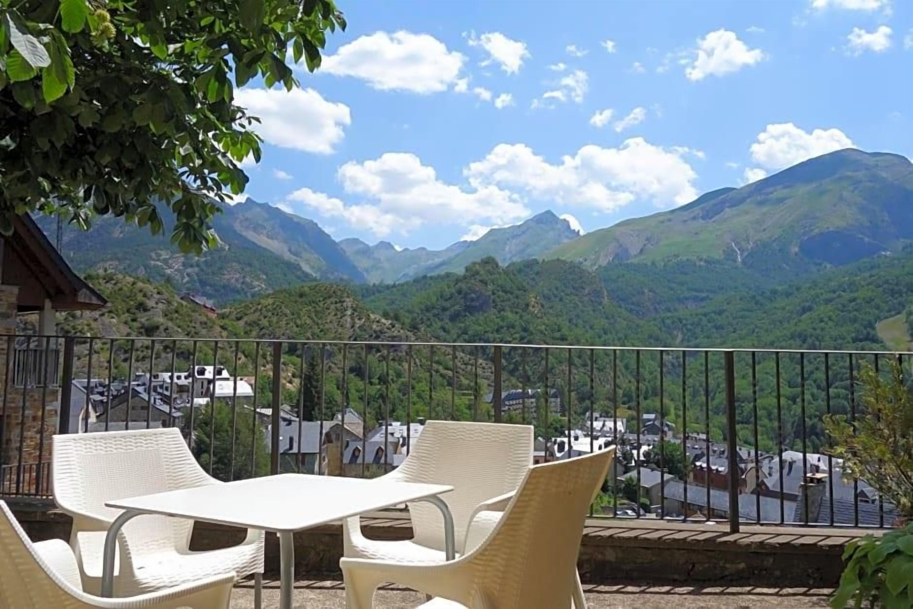 Un balcón con mobiliario de mimbre con vistas a un paisaje montañoso.