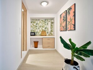 A hallway with a wooden floor, a plant, a shelf with decorative items, and two framed pictures on the wall. - The Tree Skiathos (Skiathos)