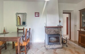 Ein Essbereich mit einem Holztisch und Stühlen, einem Kamin mit Steinverkleidung und einem Spiegel an der Wand.