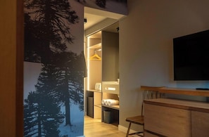 A modern room with a wooden cabinet, a television, and a closet with shelves and hanging space. - El Refugio Knapp (San Carlos de Bariloche)