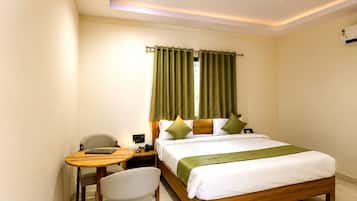 Una habitación de hotel con cama, escritorio, silla y ventilador de techo.