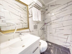 A bathroom with a white sink, a mirror with a gold frame, a shower, and a toilet. - Castle Light Boutique Otel (Alanya)